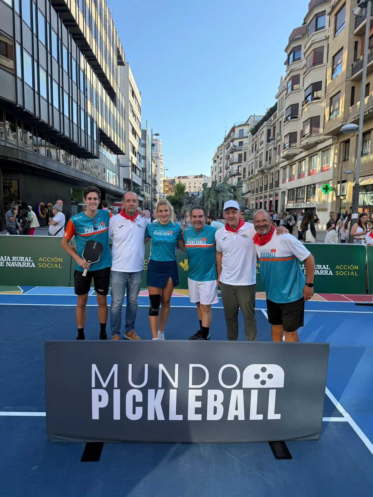 Equipo de Mundo Pickleball posando en la pista portatil del evento Dink & Roll de Pamplona frente al Monumento al Encierro