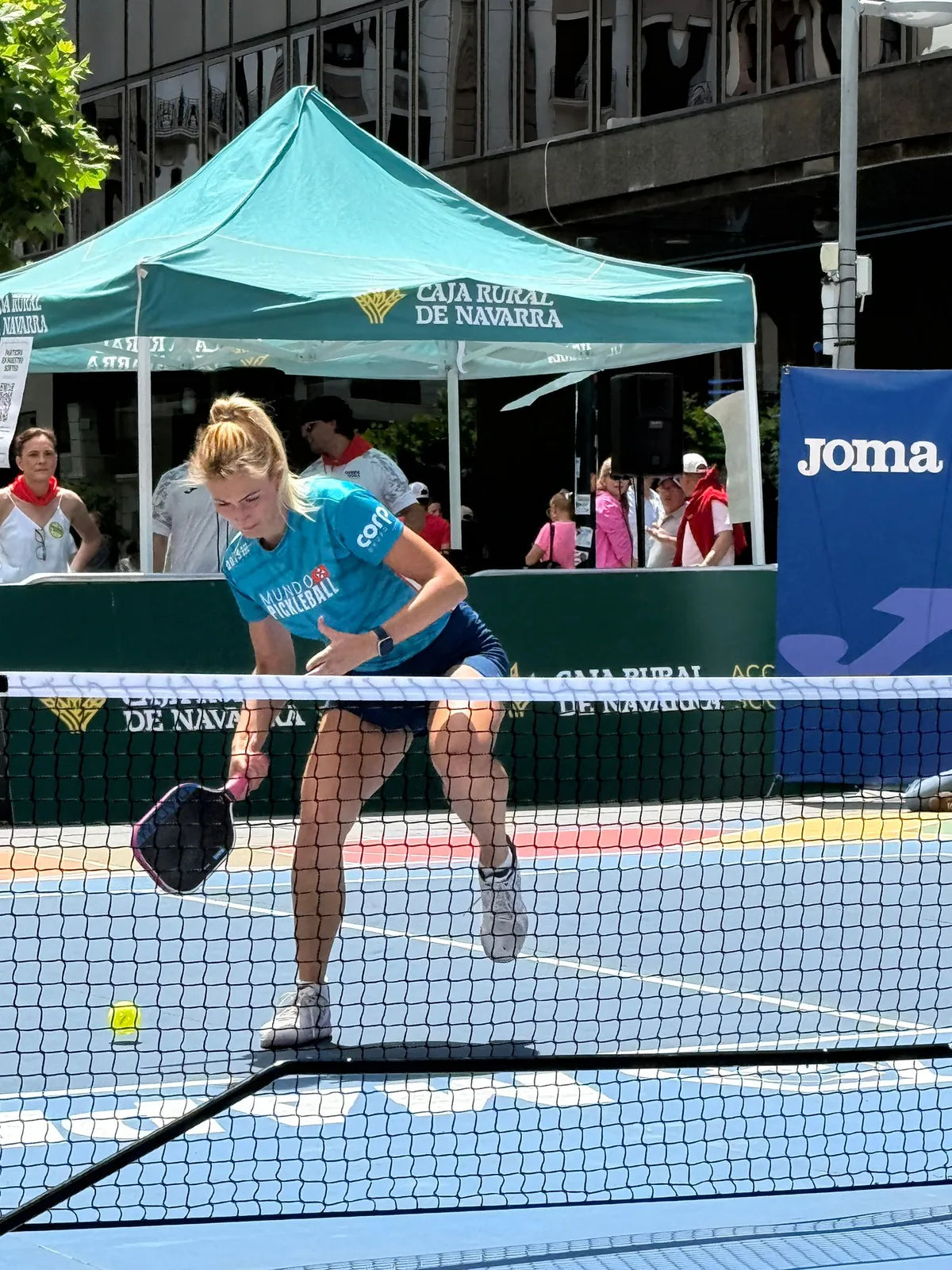Jugadora profesional golpeando en la red durante una exhibicion de pickleball sobre pista portatil en Pamplona