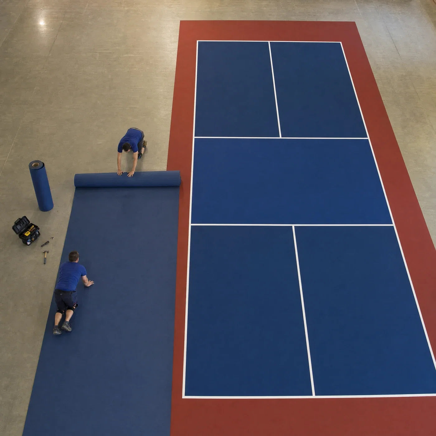 Técnicos desplegando los rollos de pavimento para montar una pista de pickleball portátil de alquiler