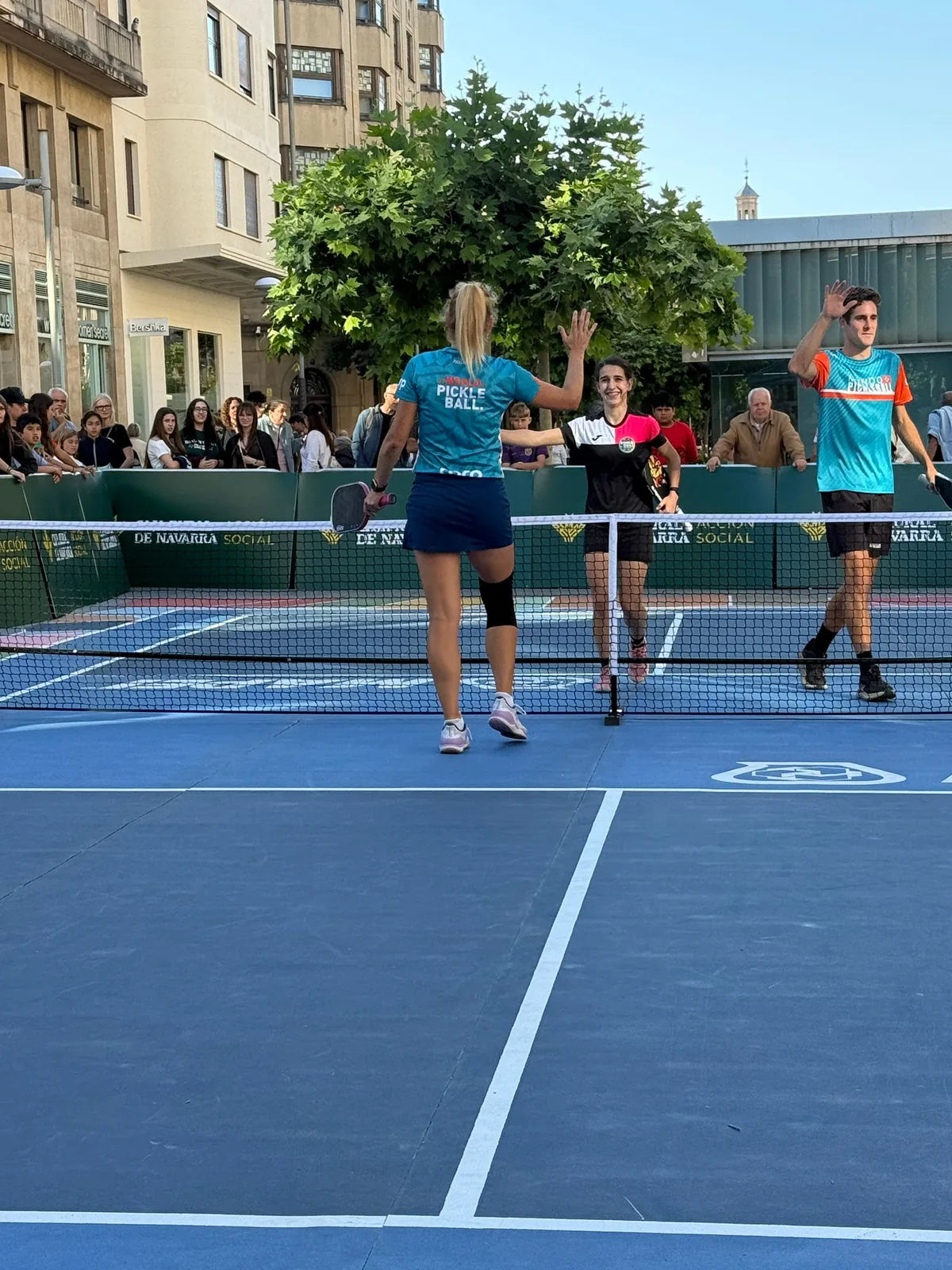 Jugadores saludandose en la red al terminar un partido de exhibicion de pickleball en evento urbano