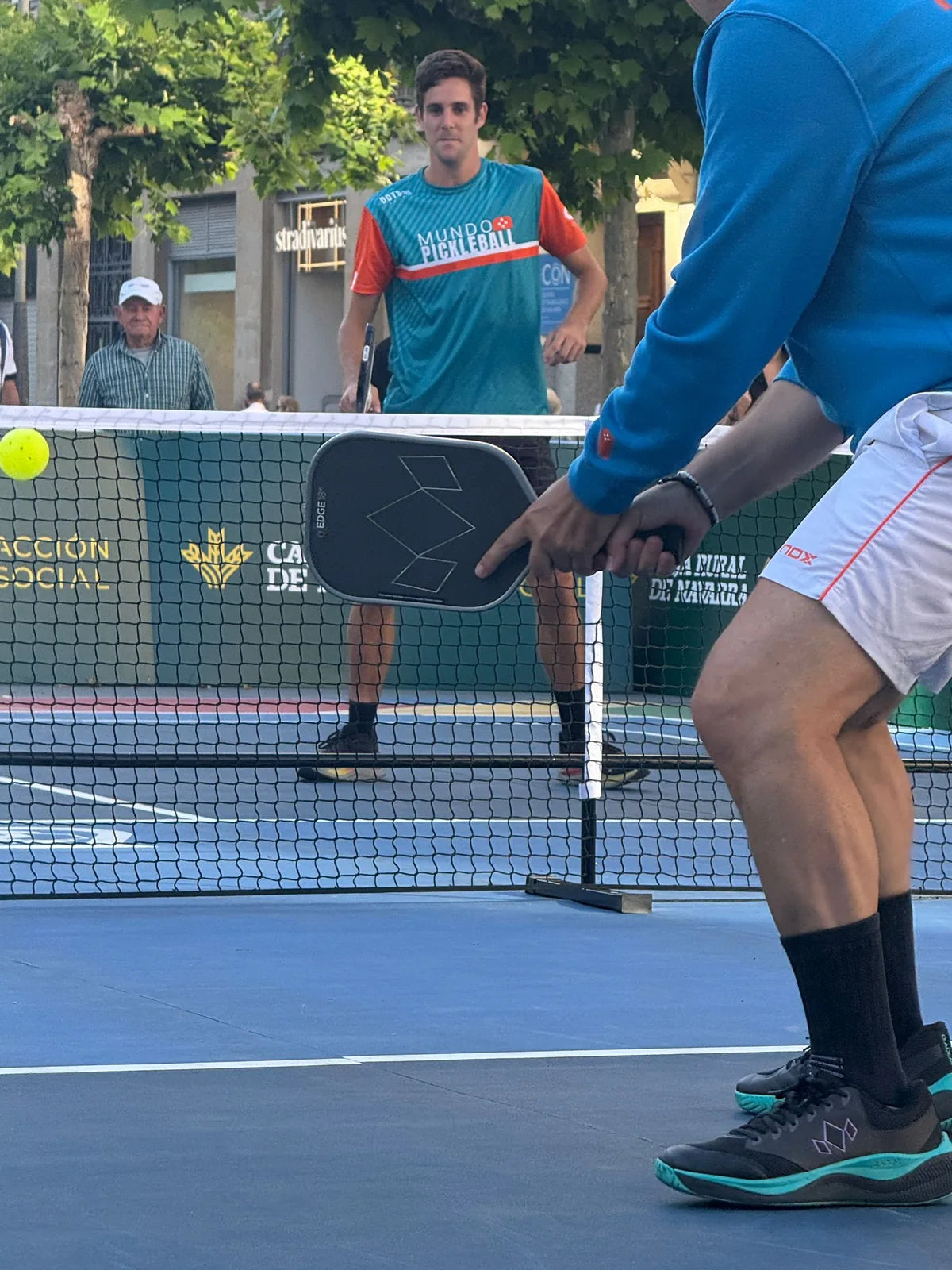 Detalle del juego de red entre dos jugadores durante un reto de pickleball en evento con animacion
